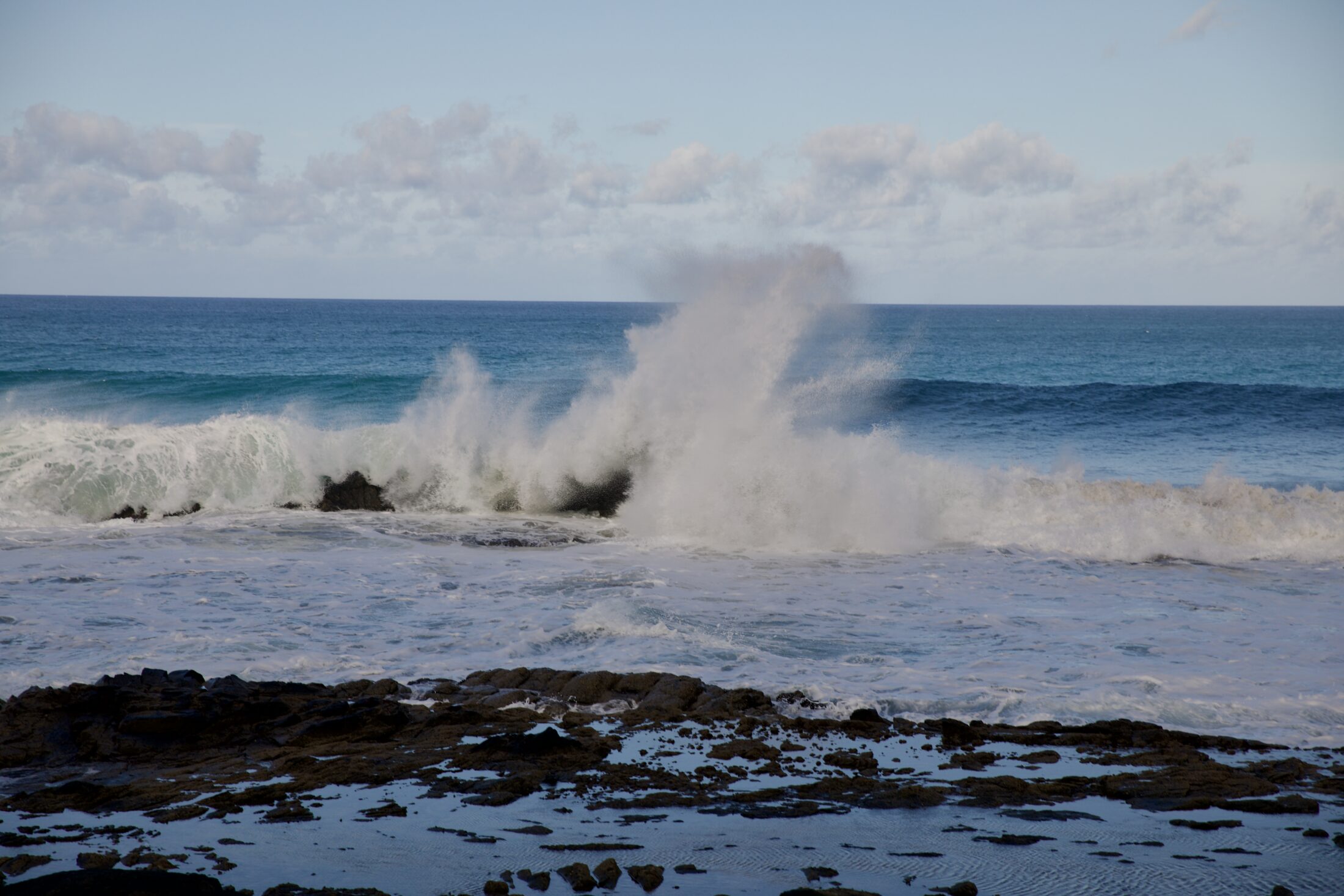 Große Wellen brechen sich an den Felssen vor der Küste
