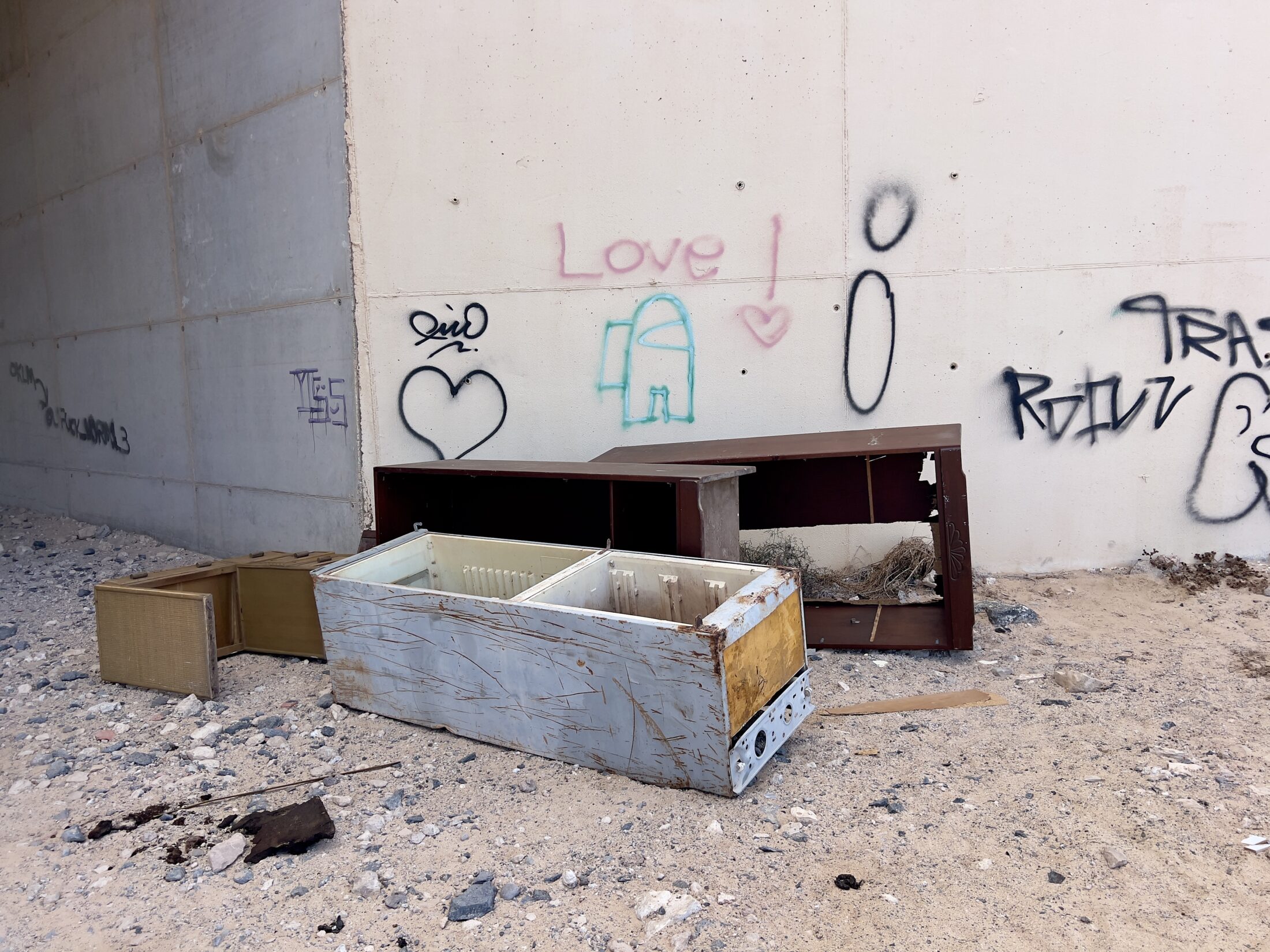 Ein ausgedienter Kühlschrank ohne Türen und ein paar ausrangierte Möbelstücke liegen bei einem Durchgang