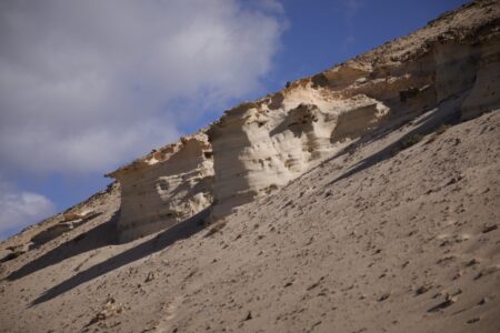 Unter einer Sandsteinklippe lägt auf einer Schräge Sand