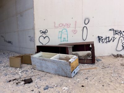 Ein ausgedienter Kühlschrank ohne Türen und ein paar ausrangierte Möbelstücke liegen bei einem Durchgang